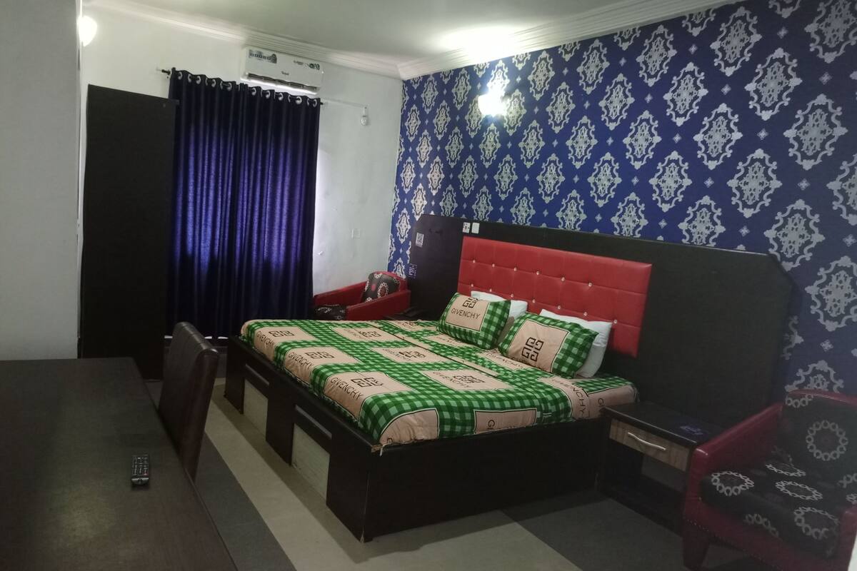 A hotel room with a bed, a desk, a chair, and a wardrobe.