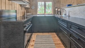 Eine Küche mit Holzwänden, einem Fenster und einem Herd.