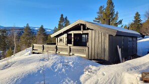 Eine Holzhütte mit Balkon, umgeben von verschneiter Landschaft und Bäumen.