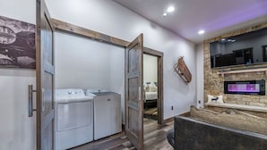 A laundry room with a washing machine and dryer, a wooden door, and a stone wall with a flat-screen TV. - Pet Friendly Outdoor Enthusiast's Retreat. Walk to Lake Dillon! (Dillon)