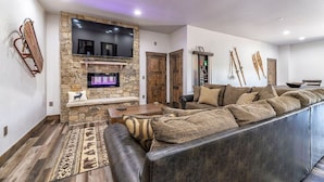 A modern living room with a stone fireplace, leather sofa, and mounted TV. - Pet Friendly Outdoor Enthusiast's Retreat. Walk to Lake Dillon! (Dillon)