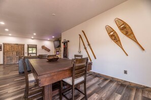 A dining area with a wooden table and chairs, a stone fireplace, and skis mounted on the wall. - Pet Friendly Outdoor Enthusiast's Retreat. Walk to Lake Dillon! (Dillon)