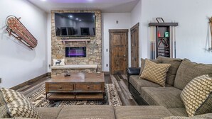 A cozy living room with a stone fireplace, a mounted TV, and a rustic wooden door. - Pet Friendly Outdoor Enthusiast's Retreat. Walk to Lake Dillon! (Dillon)