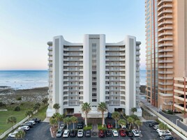 Um hotel com vários andares, entrada central e varandas em cada andar.