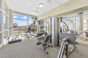 A gym with treadmills, weight machines, and a large window offering a view of the outdoors.