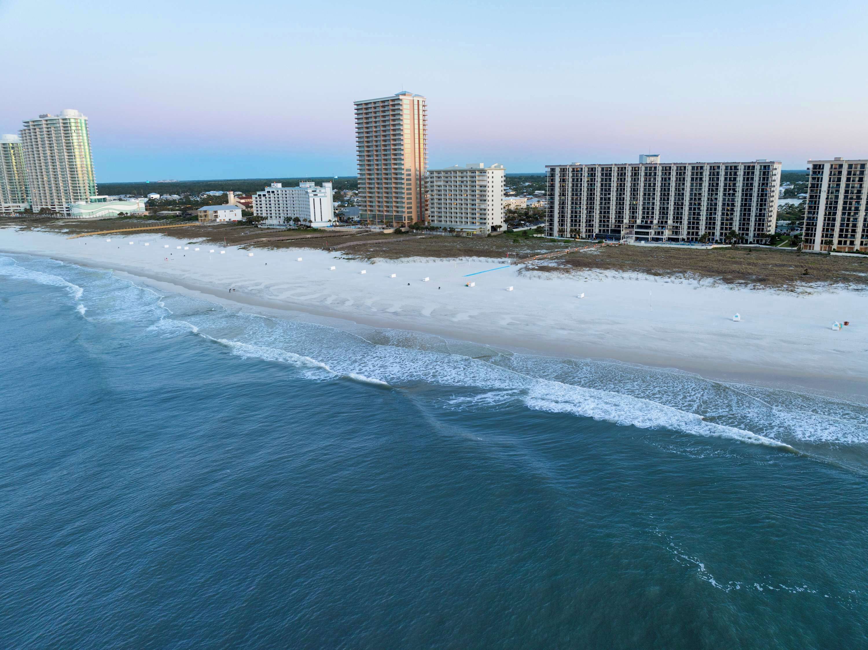 A coastal cityscape with high-rise buildings, a sandy beach, and the ocean.
