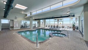 An indoor swimming pool with a sunroof, exercise equipment, and lounge chairs. - Stylish Beachfront Retreat ~ Gulf Views ~ Pools! (Orange Beach)