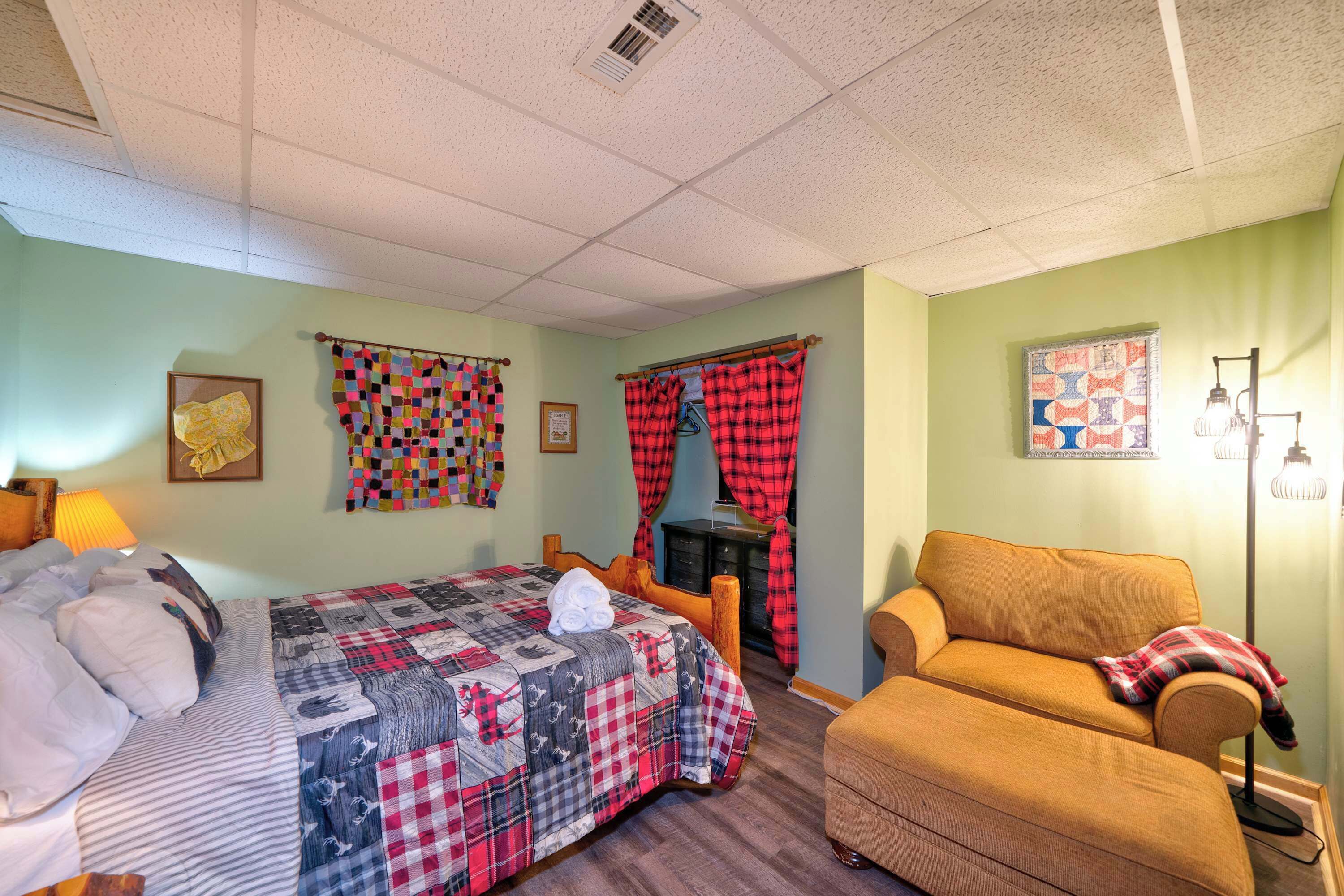 A room with a bed, a sofa, a small table, and a wall-mounted lamp.
