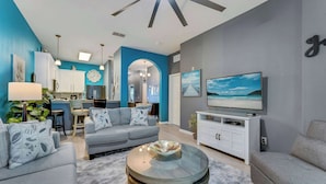 A modern living room with a grey sofa, a glass coffee table, and a flat-screen TV. - Oasis Hideaway @bahama Bay (Davenport)