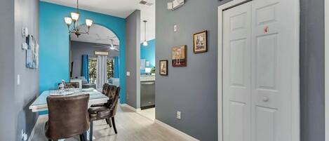 A modern dining area with a blue accent wall, a chandelier, and a white door with a sign above it.