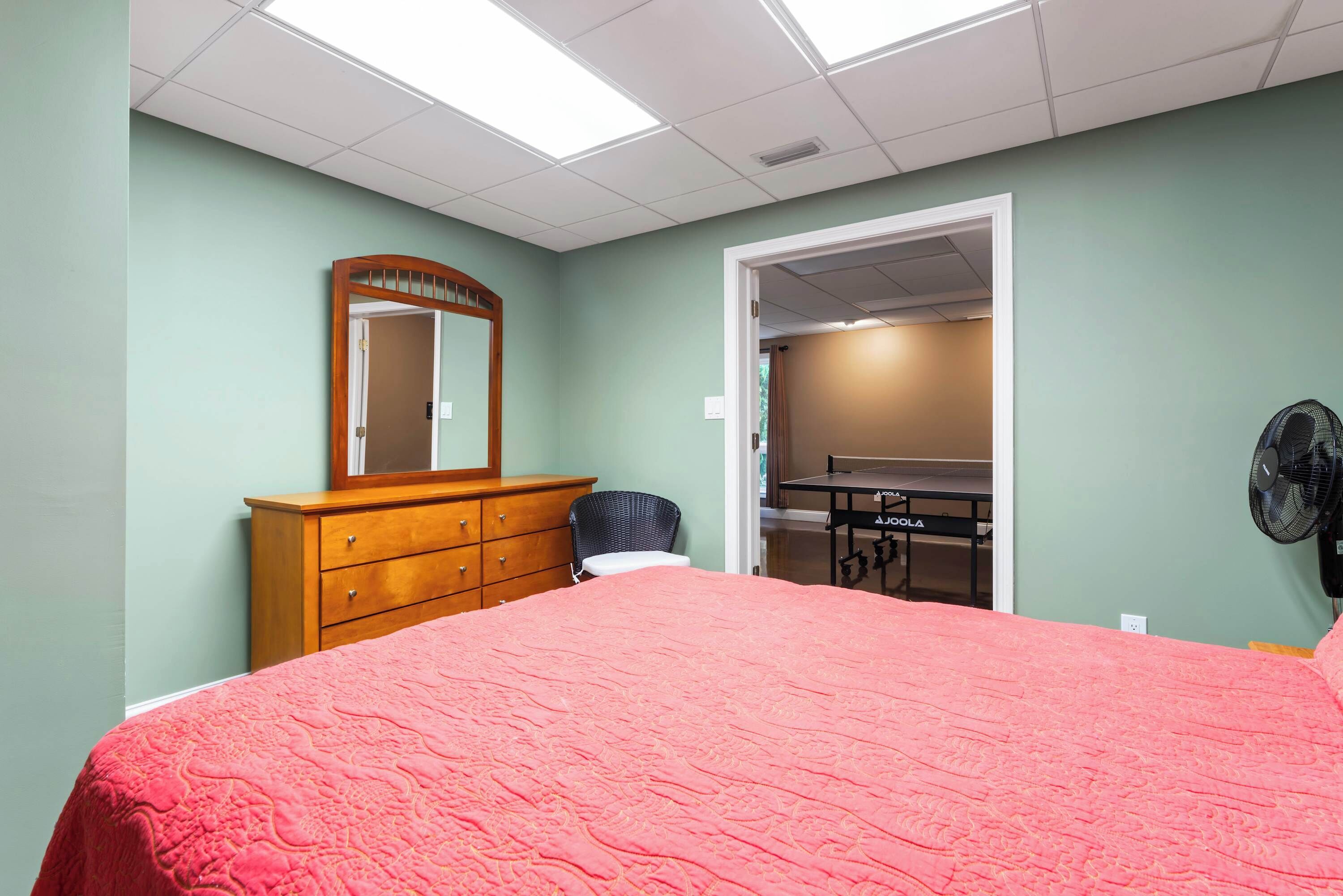 Ein Schlafzimmer mit Bett, Kommode, Spiegel und einer Tischtennisplatte.
