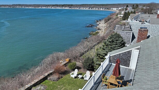 A coastal property with a deck overlooking the sea, featuring outdoor seating and a view of the shoreline. - 3BR Oceanfront on Nubble Cliffs! (York Beach)