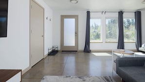 A modern living room with a grey sofa, a wooden coffee table, and a large window with curtains. - 20 Min to Mt Bachelor! Perfect Basecamp for Skiers (Bend)