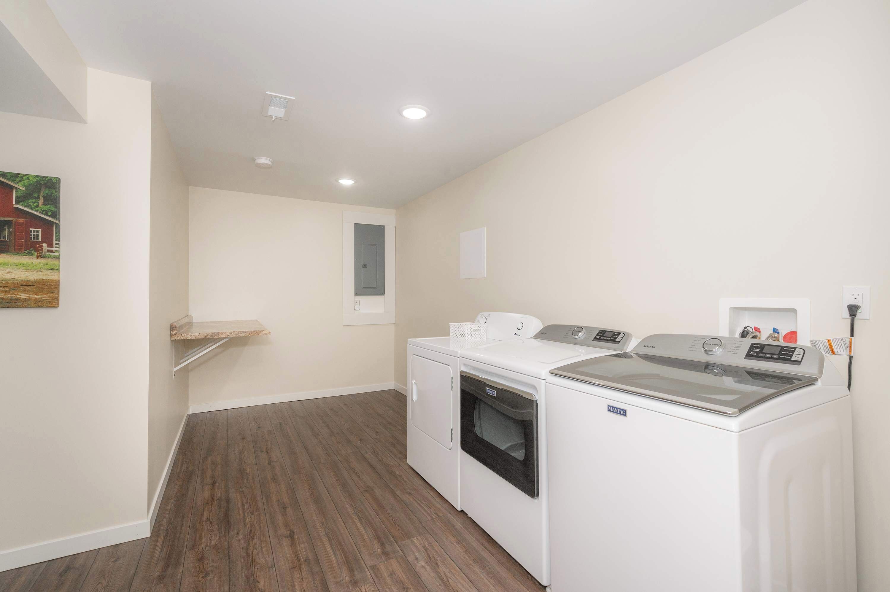 A laundry room with a washing machine, dryer, and a small shelf.