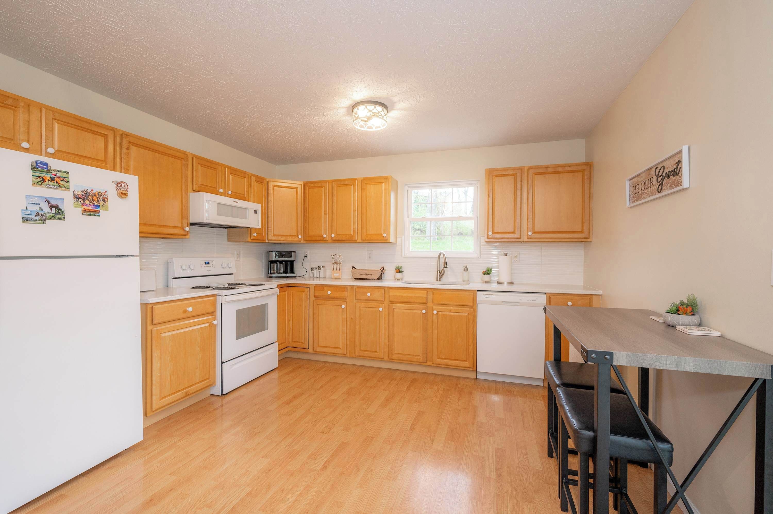 A modern kitchen with wooden cabinets, a white refrigerator, a stove, and a dining area with a table and chairs.
