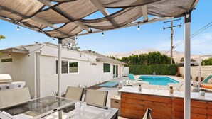 A covered outdoor patio with a glass table and chairs, a barbecue grill, a pool, and a wooden deck. - The Zen Space Private Pool! (Palm Springs)