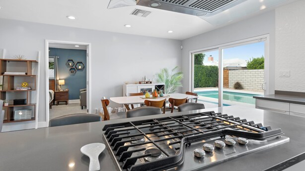 A modern kitchen with a gas stove, dining area, and a view of a swimming pool. - The Zen Space Private Pool! (Palm Springs)