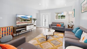 A modern living room with a flat-screen TV, sofas, a coffee table, and a patterned rug. - The Zen Space Private Pool! (Palm Springs)