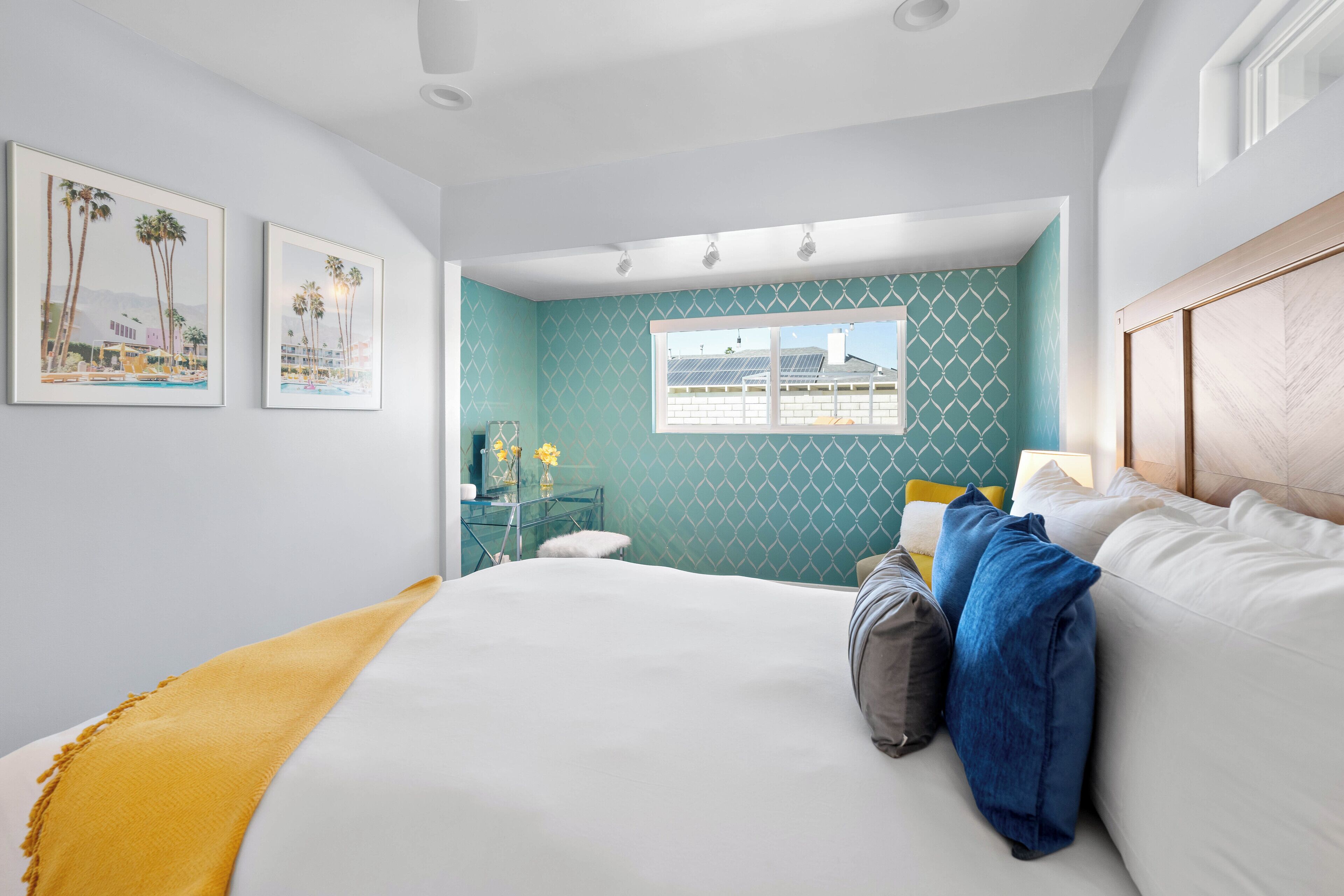 A bedroom with a large bed, a desk, and a window with a view of a building.