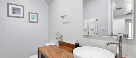 A modern bathroom with a wooden vanity, a white sink, and a large mirror.