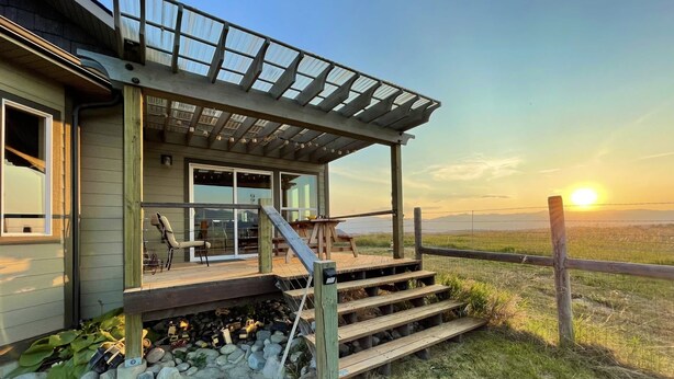 A house with a covered porch, a staircase leading to a deck, and a view of a field and mountains in the background. - Hollenback Heights Epic Views! (Eureka)