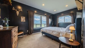 A bedroom with a bed, a dresser, a lamp, and a view of the mountains. - Hollenback Heights Epic Views! (Eureka)