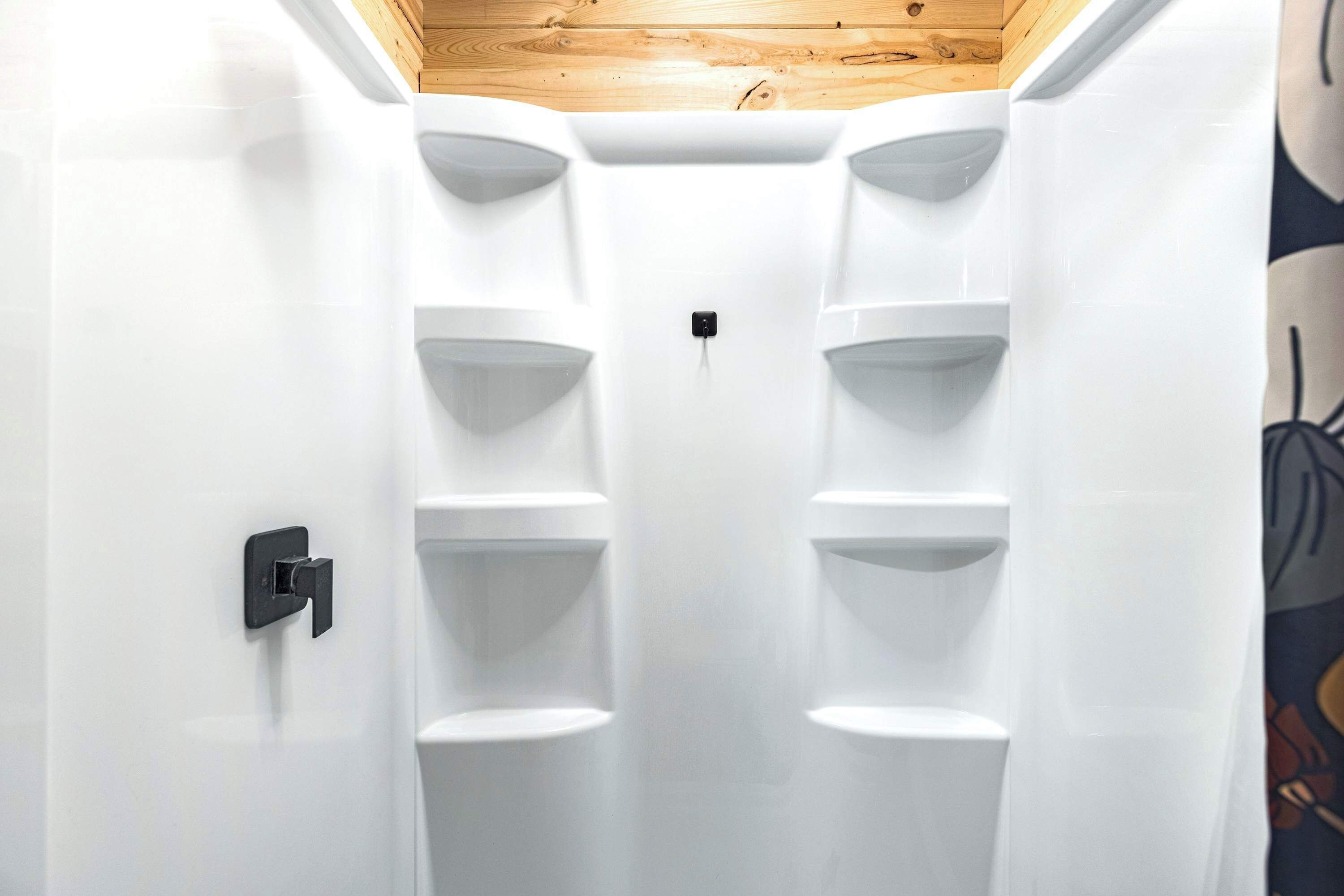 Un intérieur moderne et blanc pour un réfrigérateur compact, doté de plusieurs étagères et d’un plafond en bois.