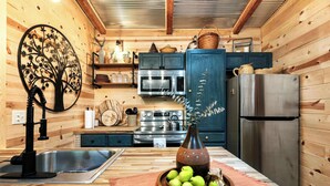 A wooden interior with a kitchen area featuring a sink, stove, oven, and refrigerator. - Cozy Cove Cabin The Perfect Ozark Retreat! (Camdenton)