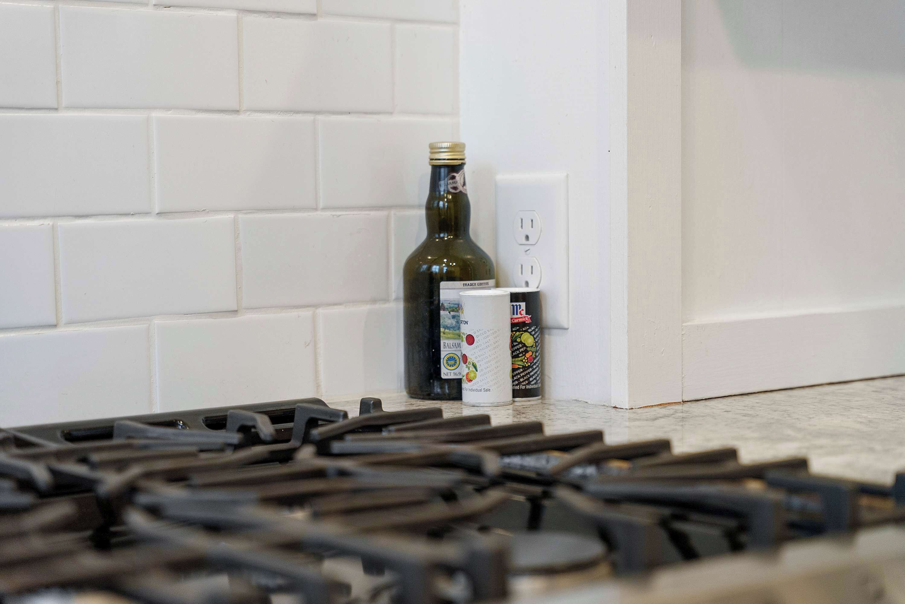 A kitchen with a gas stove, a bottle, and a can of cooking oil.