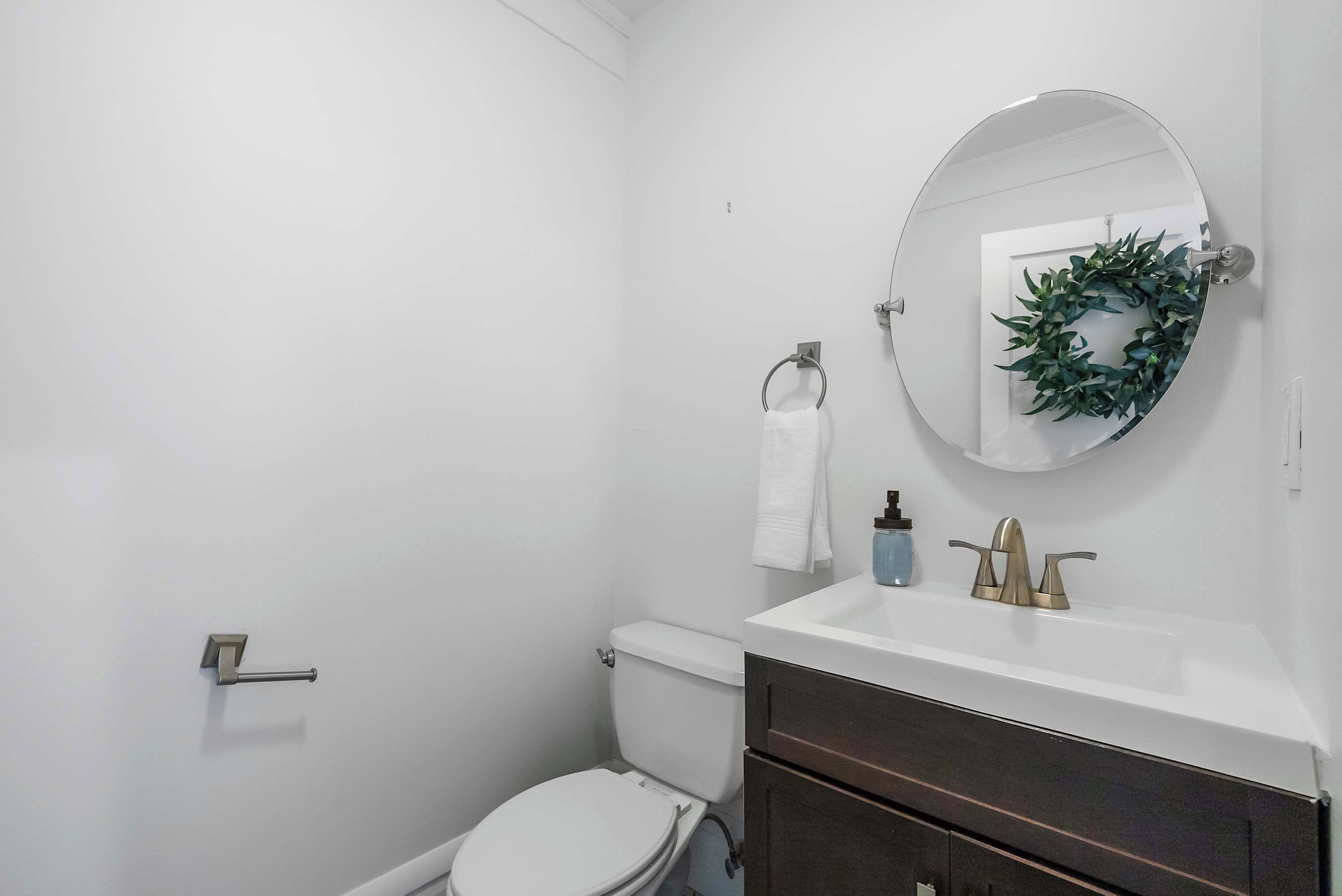 A bathroom with a white toilet, a sink with a mirror above it, and a towel hanging on the wall.