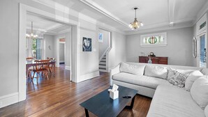 A spacious living room with hardwood floors, a dark coffee table, a light-colored sofa, and a staircase leading to another level. - Urban Elegance Getaway (Columbus)