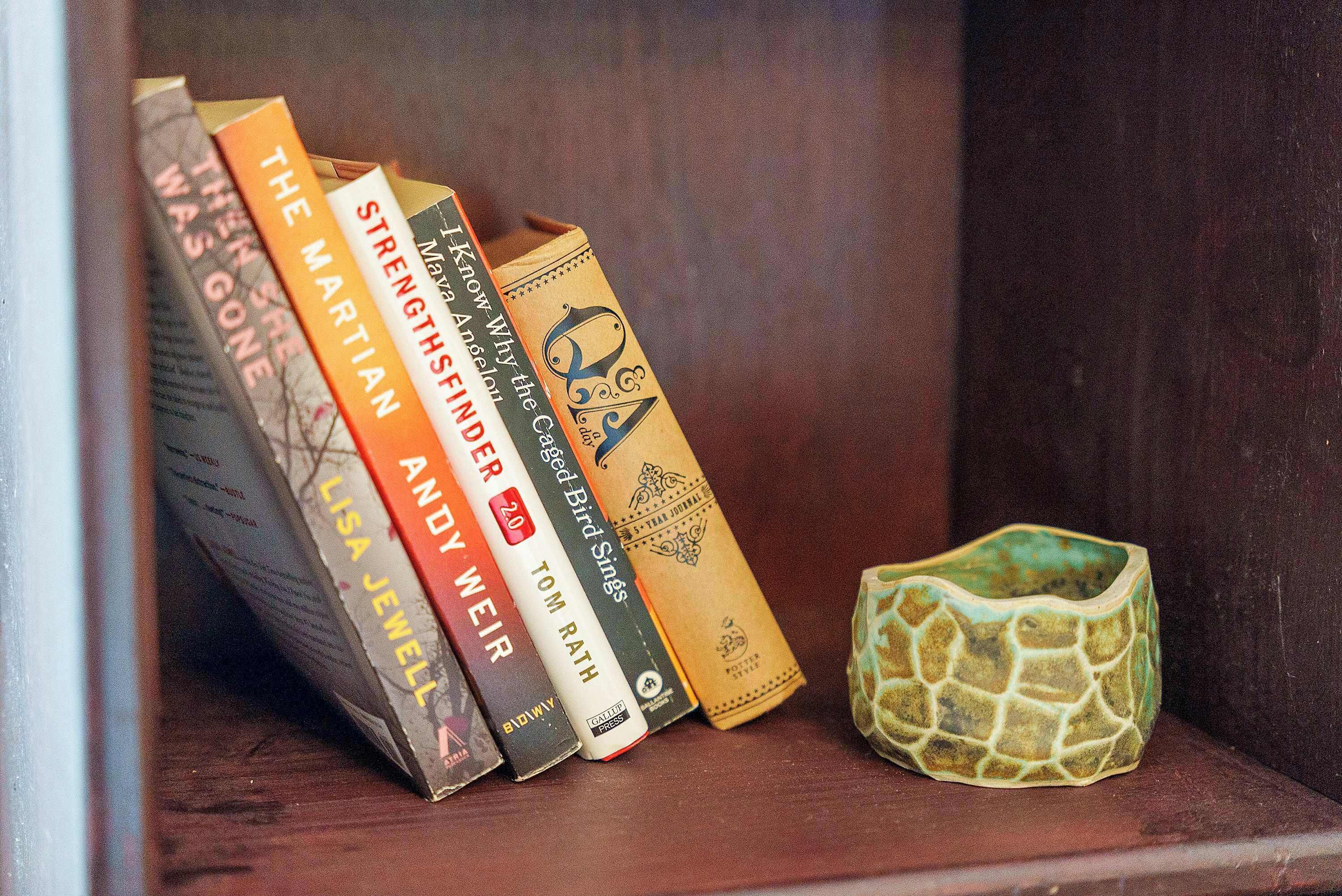 A bookshelf with books and a ceramic bowl.