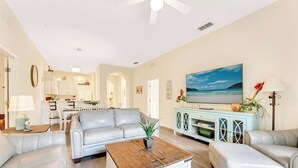 A living room with a sofa, coffee table, and TV. There is a dining area in the background. - Timeless Magic At Bahama Bay (Davenport)