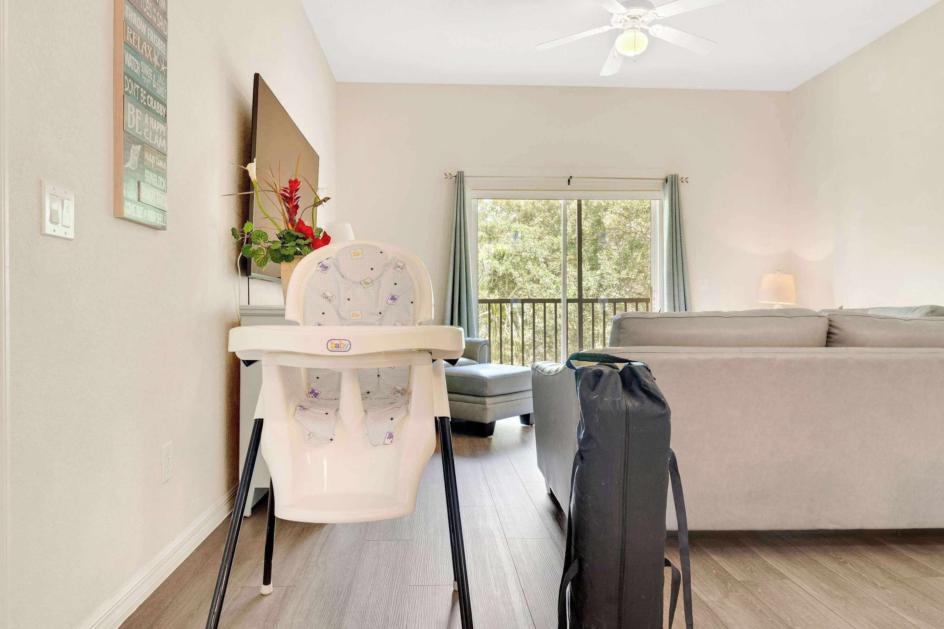 Un salon comprenant une chaise haute, un canapé, une fenêtre avec vue et un ventilateur de plafond.