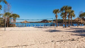 A beach volleyball court with blue netting, palm trees, and beach chairs. - Timeless Magic At Bahama Bay (Davenport)