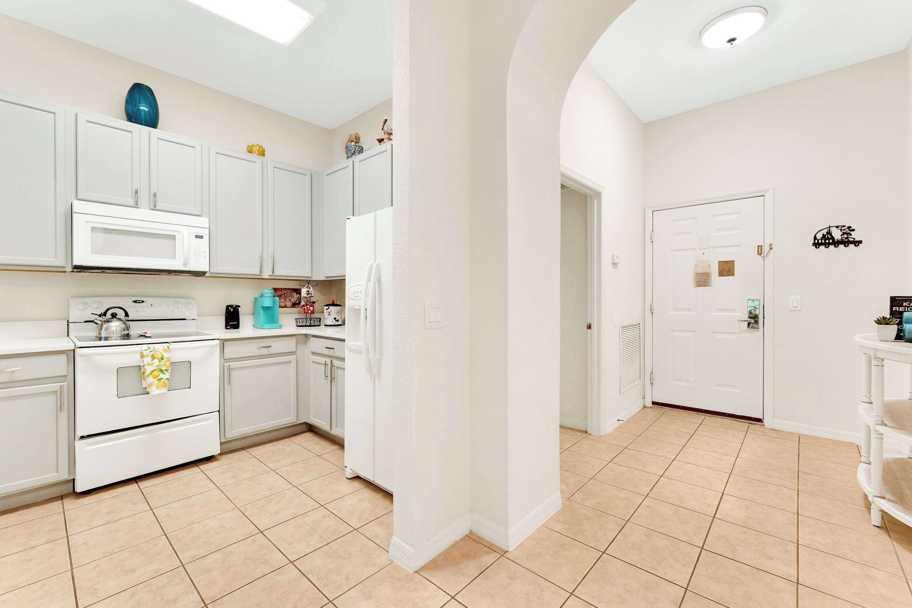 A modern kitchen with white cabinetry, a microwave, stove, and refrigerator.