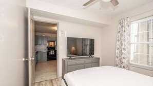 A bedroom with a bed, a TV on a dresser, and a view of the kitchen. - Arkstone Retreat 2 - 4 minutes from the Ark! (Williamstown)