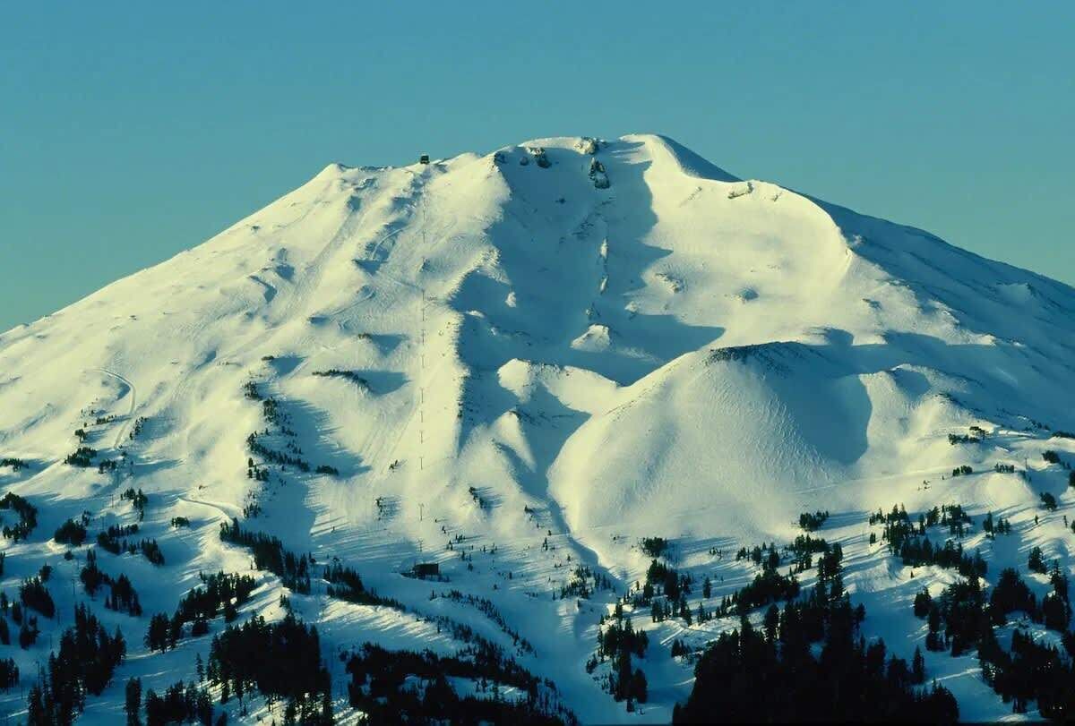 Ein mit Schnee bedeckter Berg mit Skipisten und Bäumen.