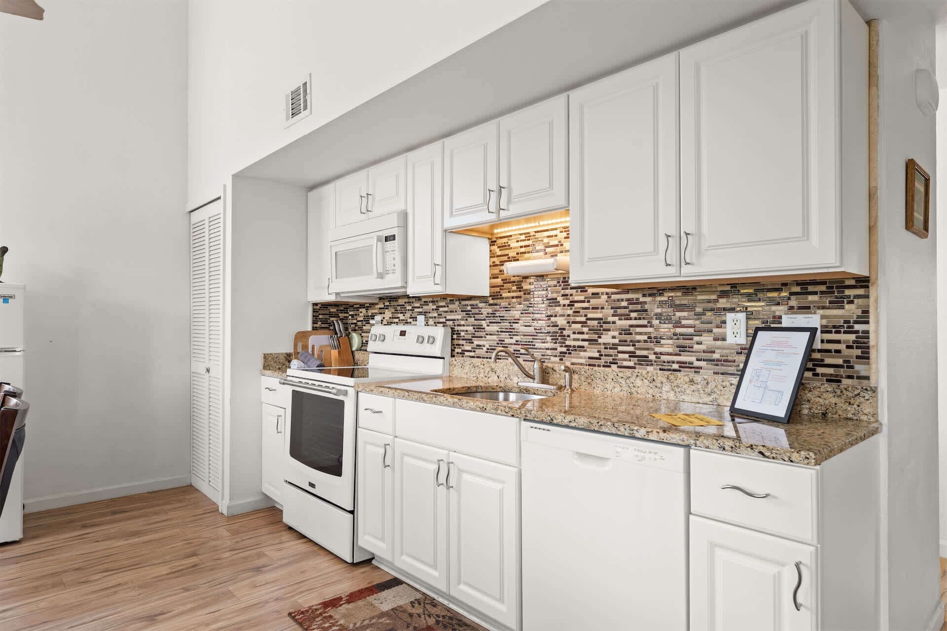 A kitchen with white cabinets, a microwave, stove, and a tiled backsplash.