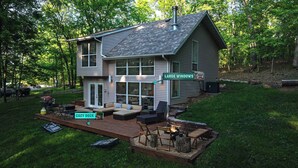 A two-story house with large windows, a cozy deck, and a fire pit. - Treehouse LOZ Seclusion for 6! (Sunrise Beach)