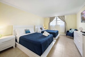 A hotel room with two beds, a nightstand, a dresser, and a window with curtains.