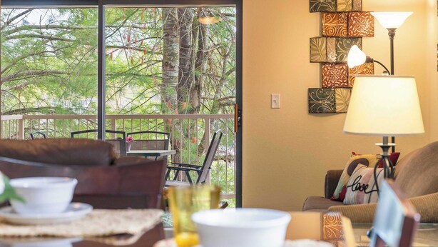 Une pièce confortable avec un balcon, meublée d’un canapé, de fauteuils et d’une table à manger, agrémentée de bols et de tasses.