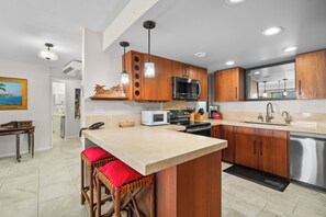 A modern kitchen with wooden cabinets, a central island, stainless steel appliances, and pendant lighting. - (4102/03) 2Br Ground Floor Hanalei Bay Resort, Ocean View, Pool, Tennis (Princeville)