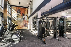 A gym with cardio equipment, weight machines, and a large mural.