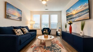 A living room with a sofa, armchair, coffee table, and artwork on the walls.