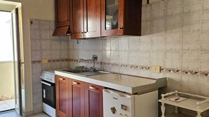 Une cuisine avec des meubles en bois, un réfrigérateur blanc, une cuisinière et un pare-feu en carreaux.