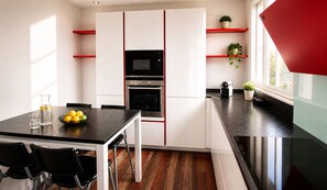 A modern kitchen with a black countertop, white cabinets, and red accents.