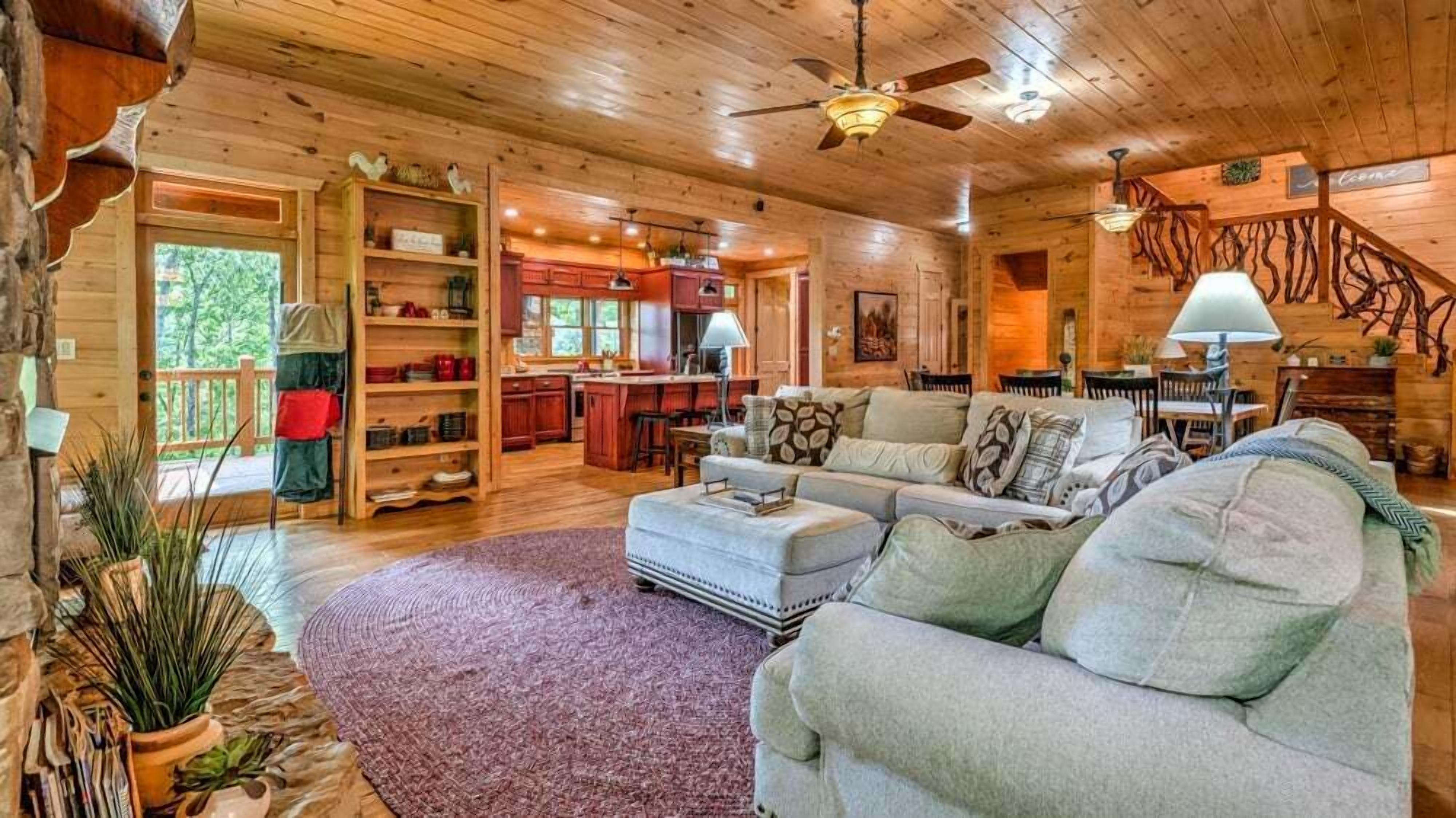 A cozy cabin interior with a living room, kitchen, and dining area.