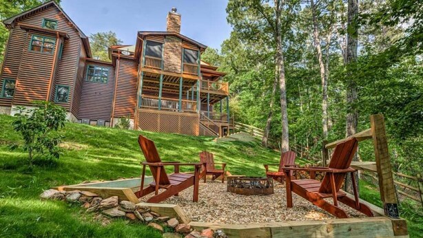 Un chalet rustique doté d’une cheminée en pierre, d’une terrasse en bois et d’un espace extérieur aménagé avec un foyer.