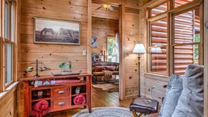 L’intérieur d’un chalet accueillant, avec des murs en bois, un lit, un bureau et une fenêtre donnant sur le paysage extérieur.